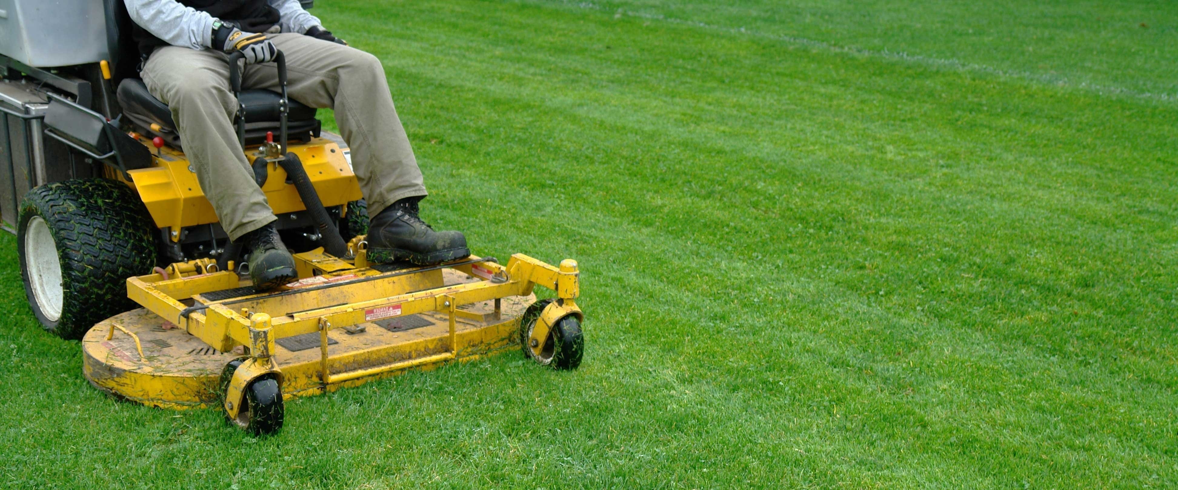 guy cutting grass on a lawnmower